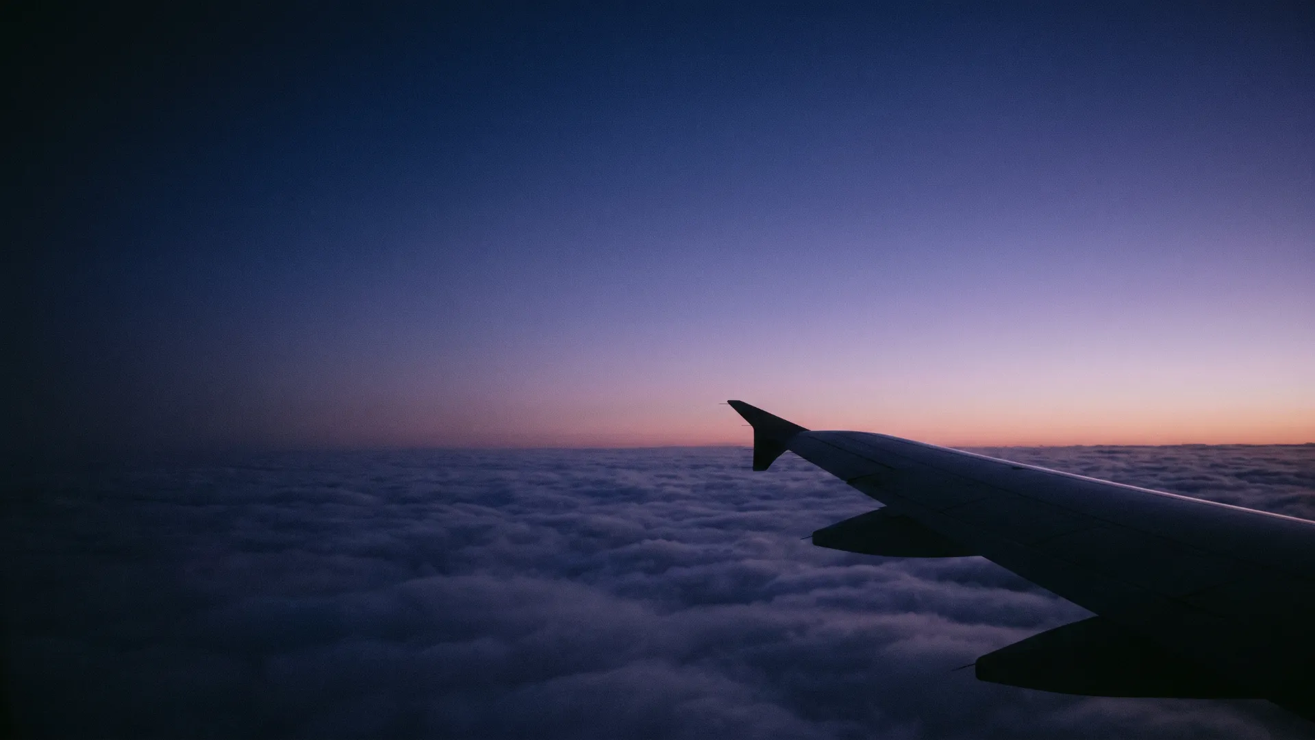 A sea of clouds at dawn from a window seat, the sky indigo to violet.